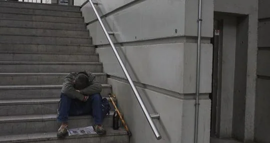 Acompañado de una litrona, un joven dormita en las escaleras de la estación
