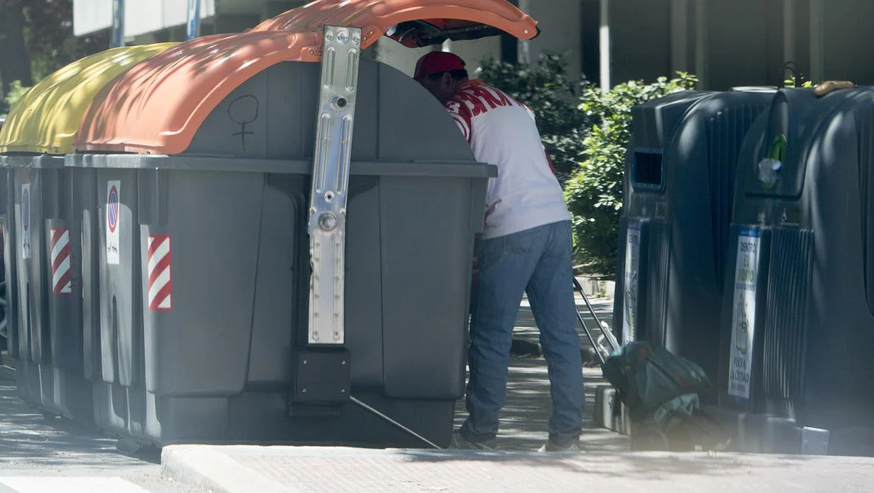 Un hombre rebusca entre la basura en Orcasitas, ayer