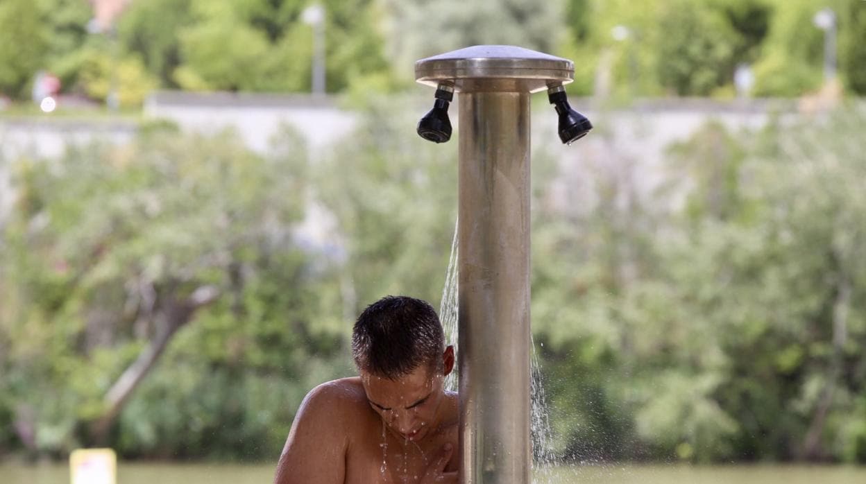 Un jóven refrescándose en la ducha de la playa de las Moreras en Valladolid