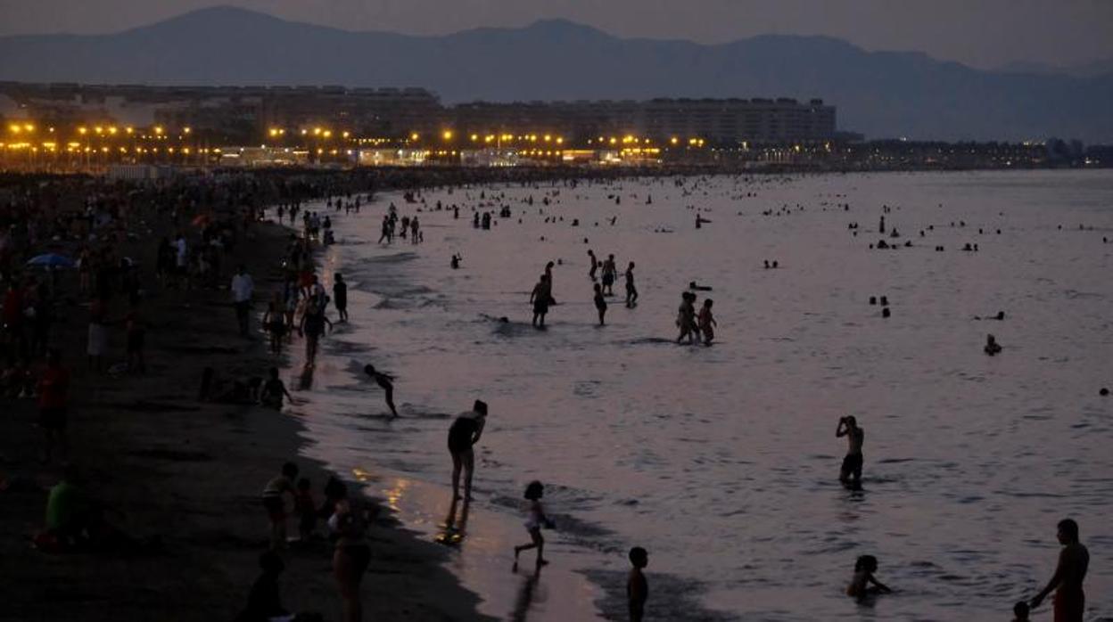 Bañistas en la playa de Valencia por la noche, este sábado con el litoral todavía atestado de gente