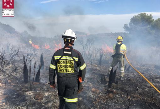 Bomberos trabajando en la extinción del incendio provovado por el coche en llamas