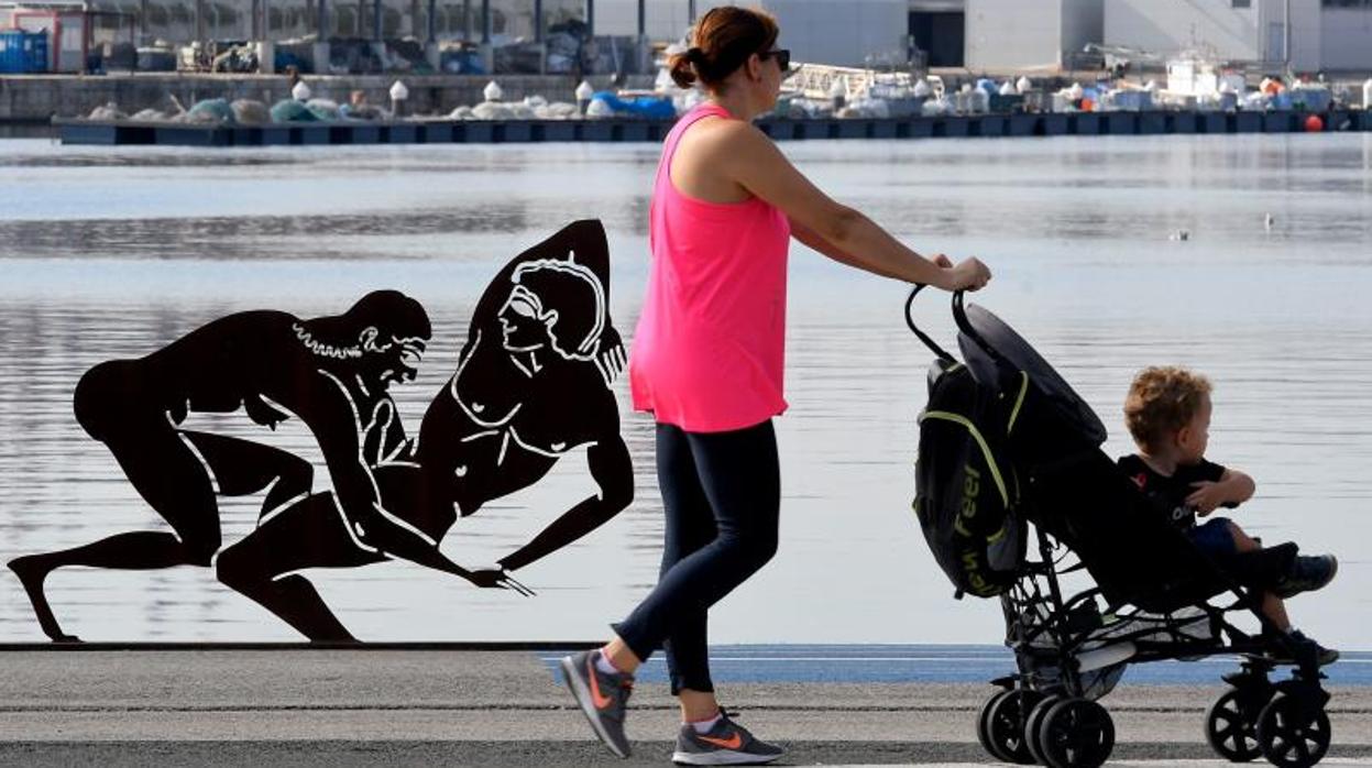 Una mujer paso con un niño pequeño en un carrito junto a una de las esculturas de Miró en Valencia