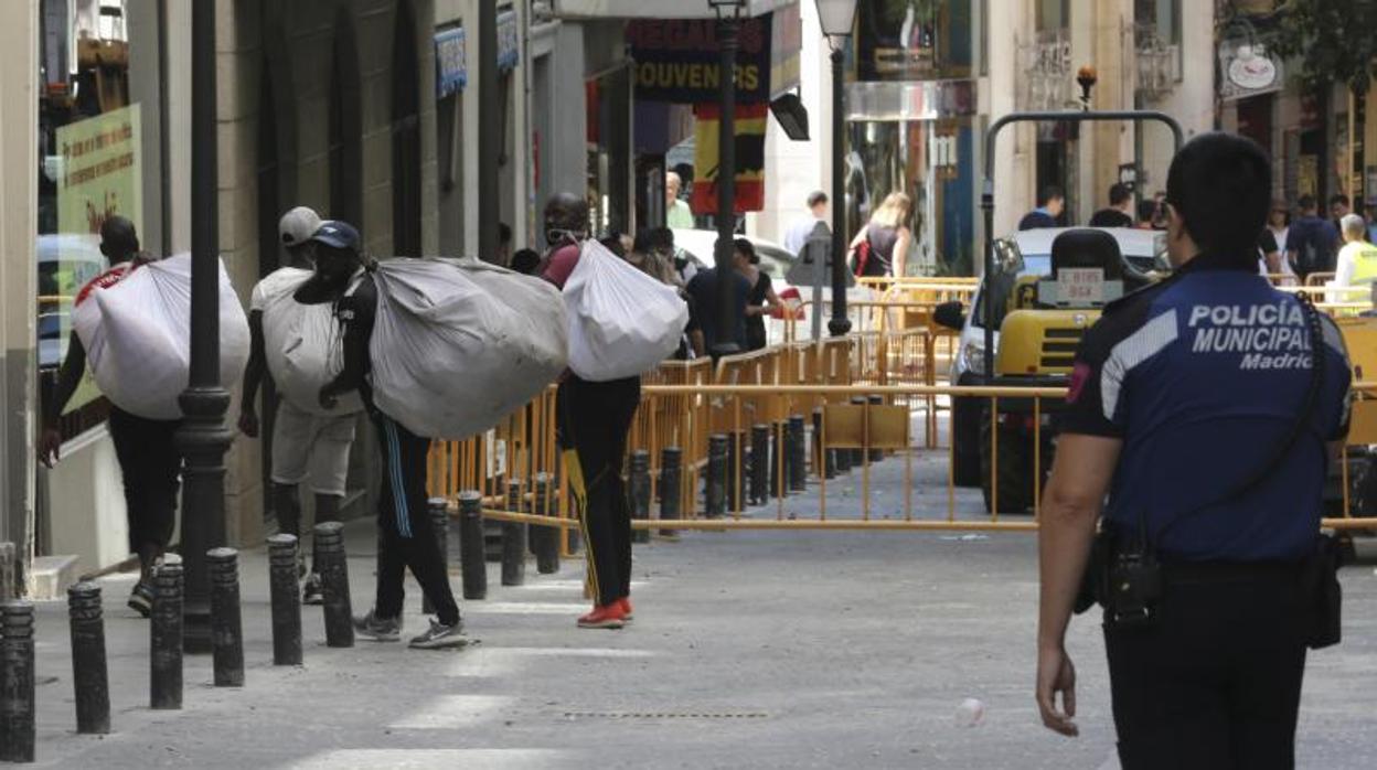 Unos manteros recogen la mercancía ante la presencia policial