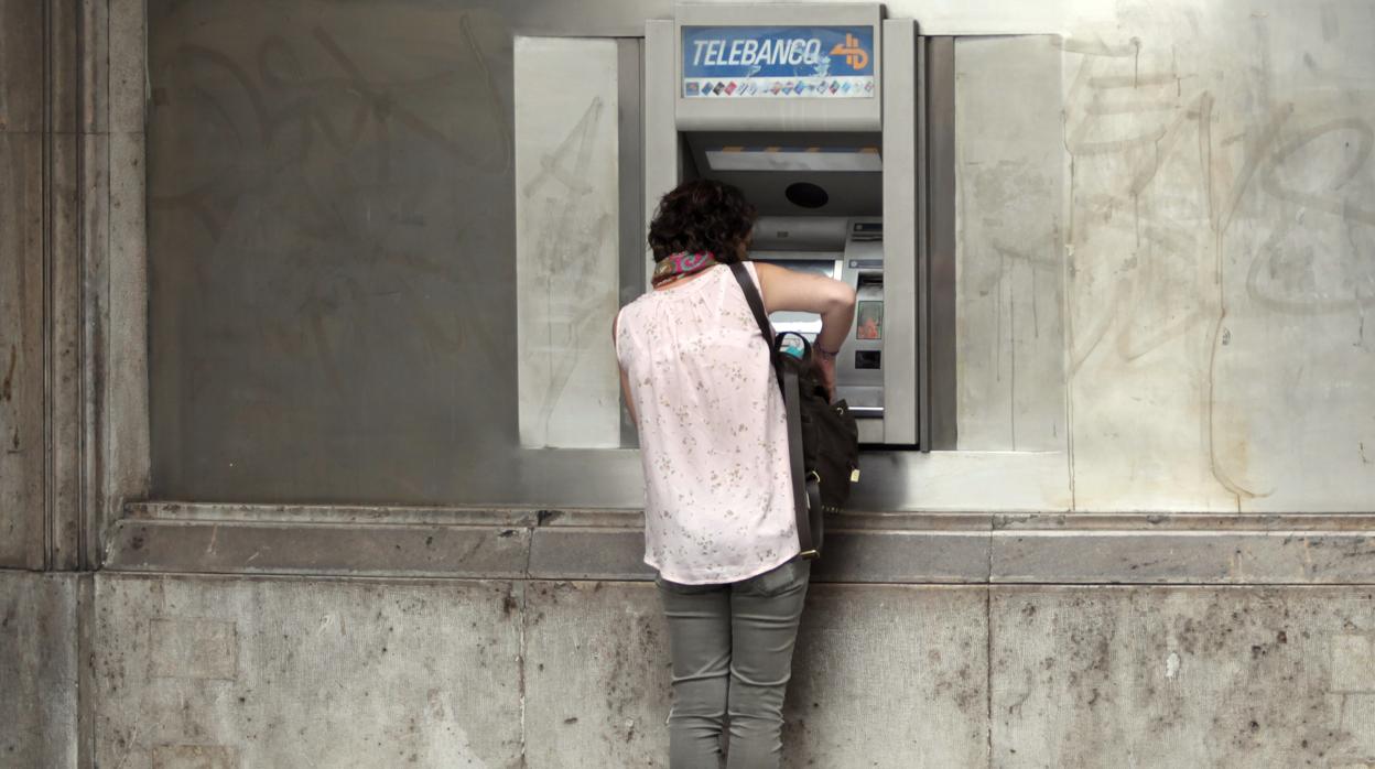Una mujer extrae dinero de un cajero automático