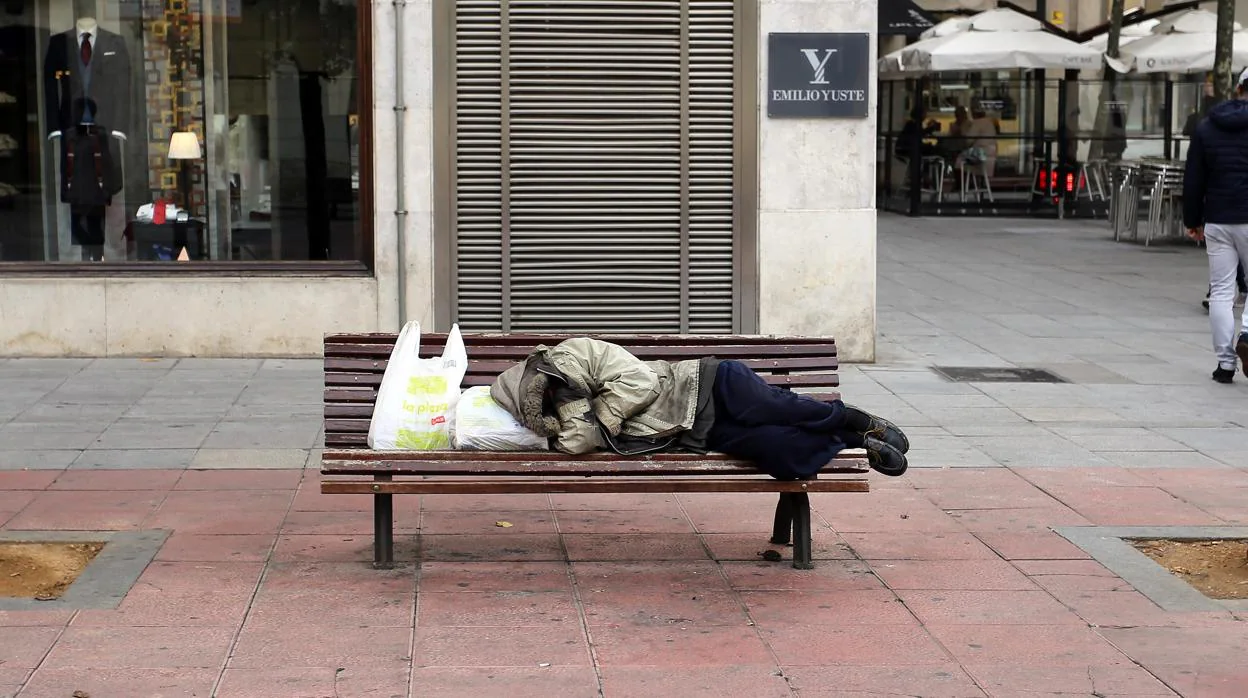 Indigente durmiendo en un banco de la plaza de Santa Ana de Valladolid