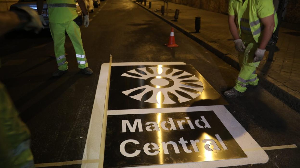 Operarios del Ayuntamiento instalando las señales de Madrid Central en la calzada