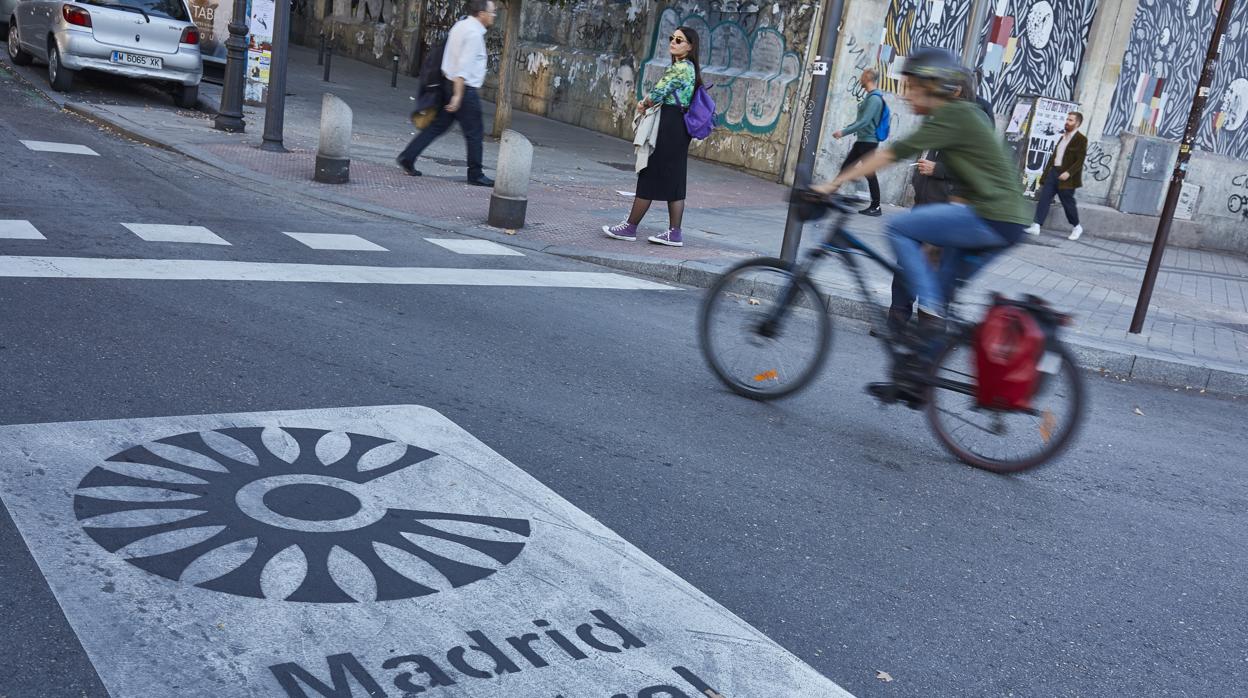 Un ciclista pasa junto a una señal horizontal de Madrid Central, el ámbito con restricciones al tráfico privado que se pondrá en marcha el 30 de noviembre