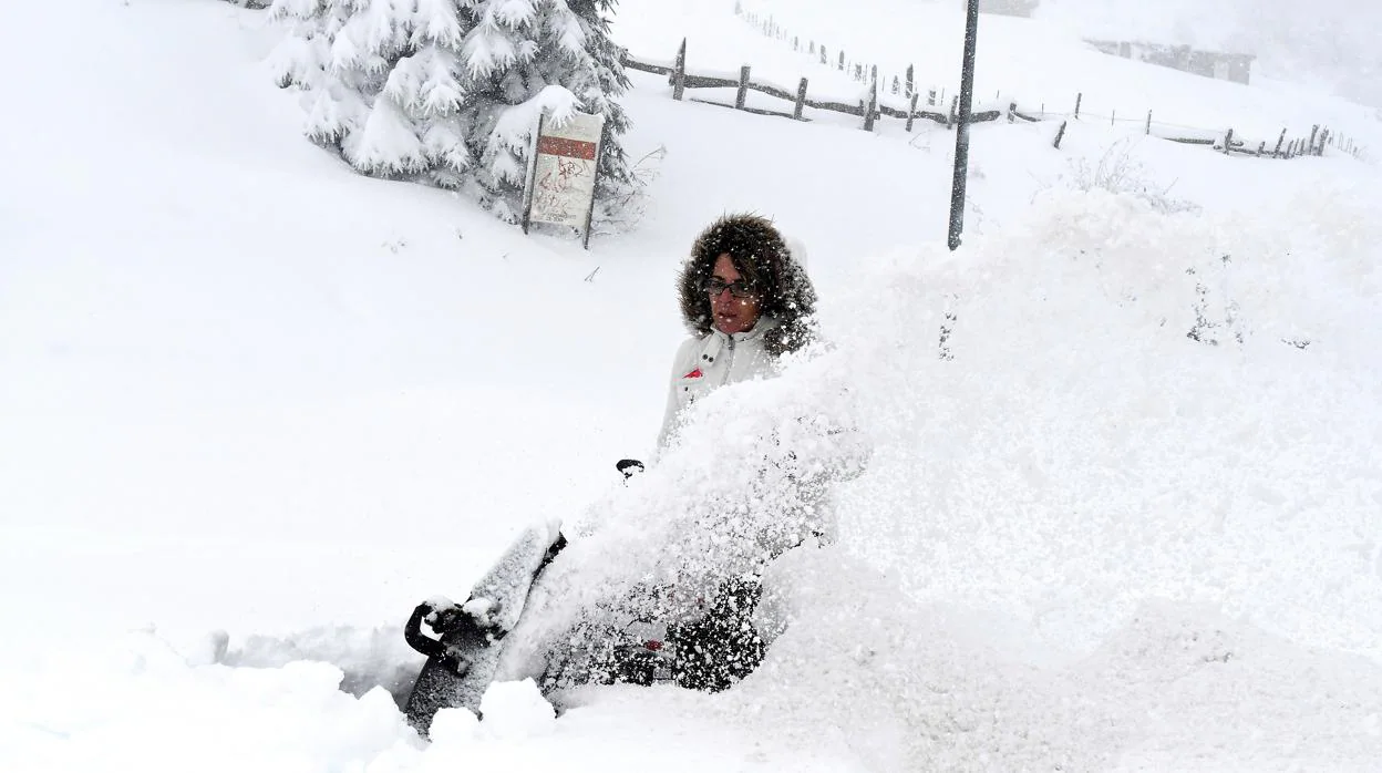 Una mujer trata de despejar la nieve en Pajares