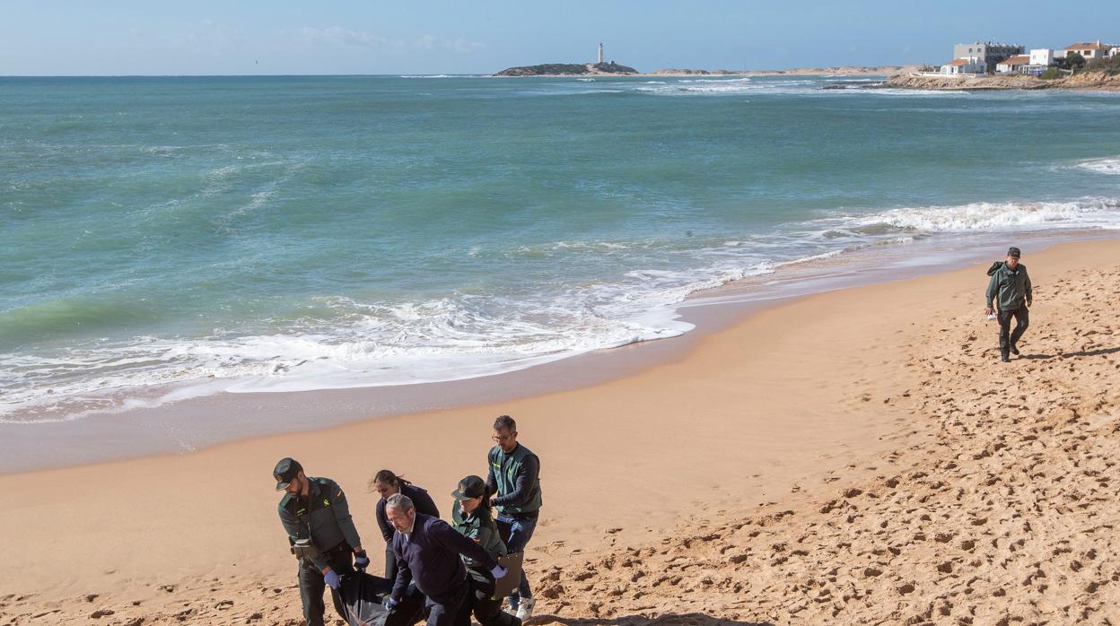 Agentes de la Guardia Civil y operarios, trasladan el décimo cadáver hallado de los ocupantes de la patera que naufragó el pasado lunes en la playa de Caños de Meca