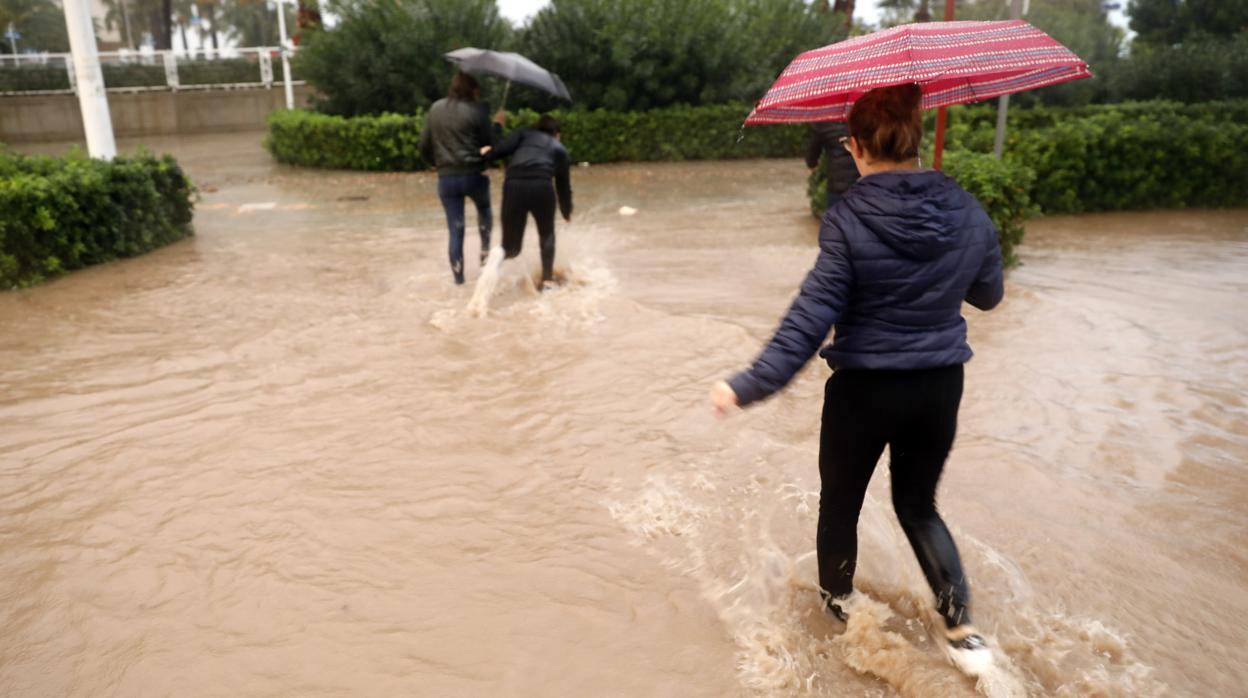 Varias personas cruzan una calle inundada en Valencia el pasado viernes