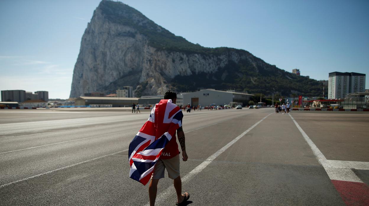 Un residente en Gibraltar camino por el aeropuerto con el Peñón de fondo
