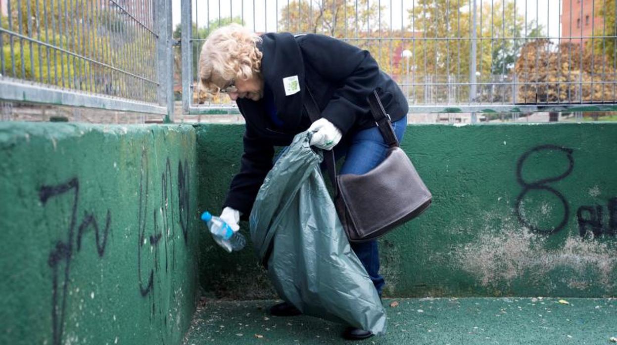 La alcaldesa de Madrid, Manuela Carmena, ayer, recoge una botella de plástico del suelo en Puente de Vallecas