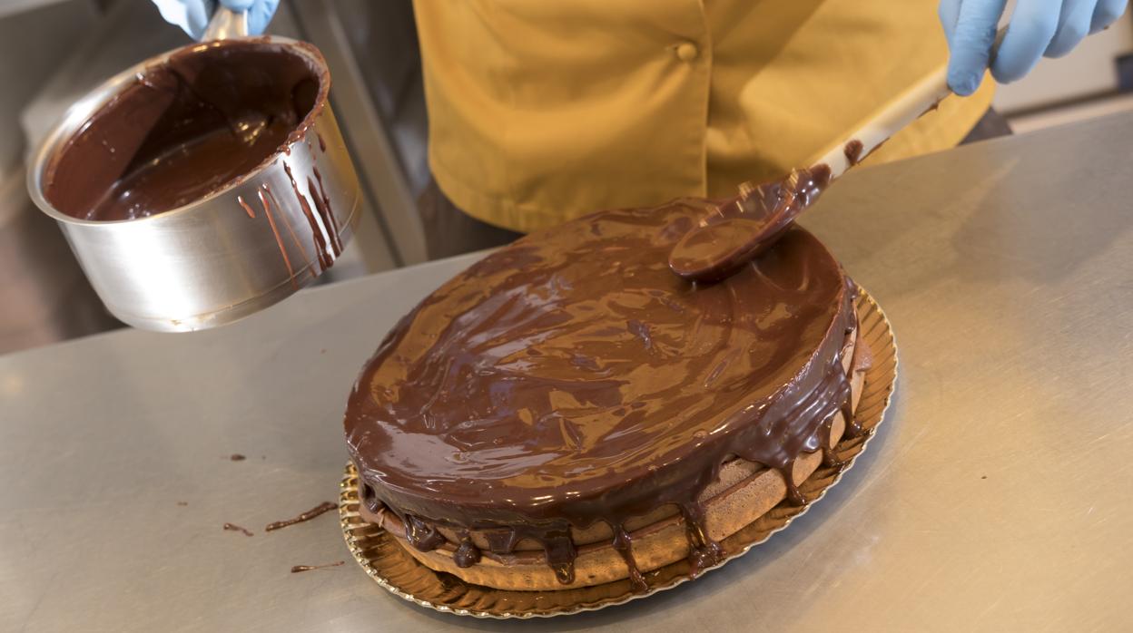 Un repostero realiza una tarta de chocolate y bizcocho