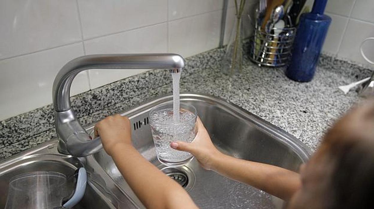 Imagen de archivo de una niña con un vaso de agua del grifo