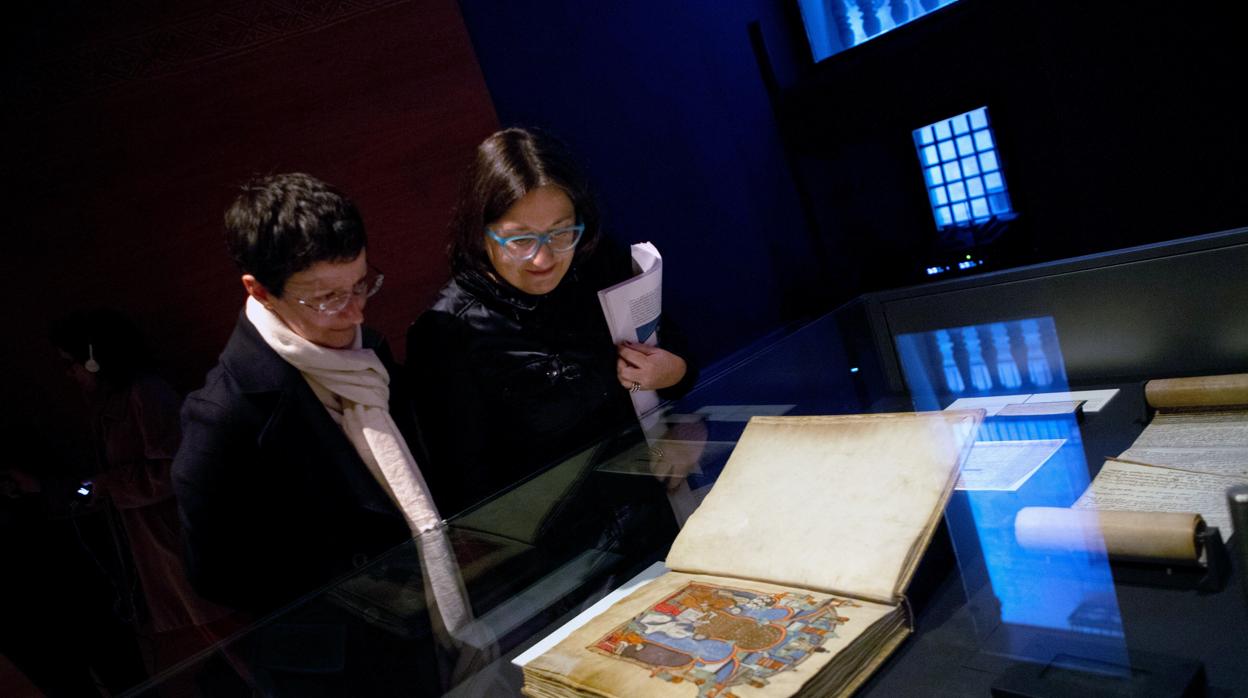 Dos visitantes observan el Gran Libro de los Feudos, un cartulario de documentos relativos a las relaciones feudales de los reyes de Aragón y condes de Barcelona