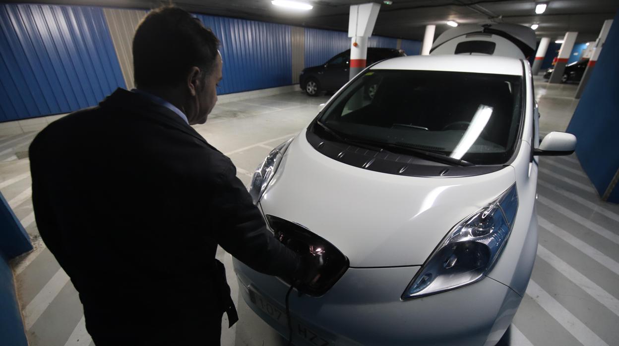 Un hombre carga un coche eléctrico en un garaje