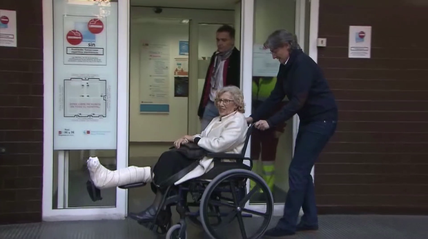 Carmena recibe el alta y sale en silla de ruedas del hospital de La Princesa