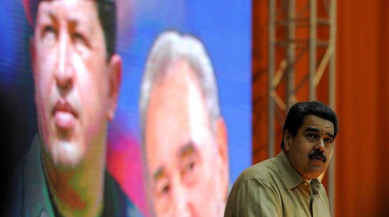 Nicolás Maduro en un acto público, con la imagen detrás de Hugo Chávez y Fidel Castro