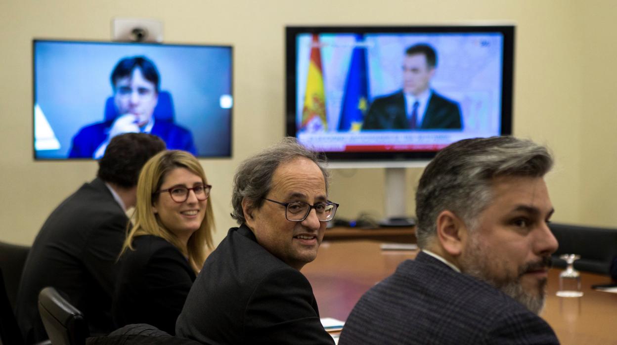 Los dirigentes de Junts per Catalunya con pantallas en las que aparecen Pedro Sánchez y Carles Puigdemont