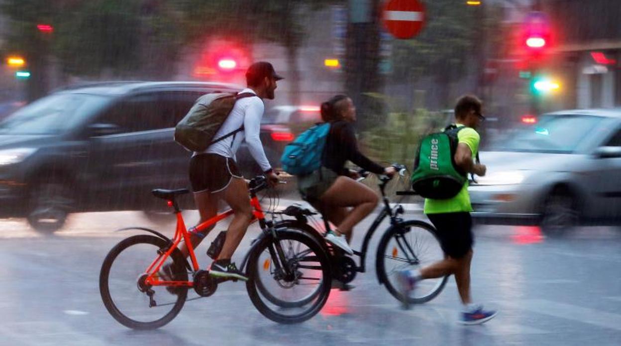 Ciclistas circulando por Valencia bajo la lluvia