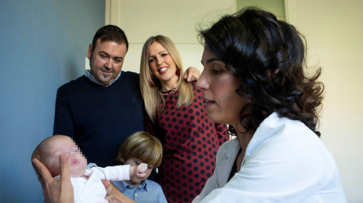 La doctora Sarquella con María en brazos. Detrás, los padres de la pequeña y su hermano Mateo