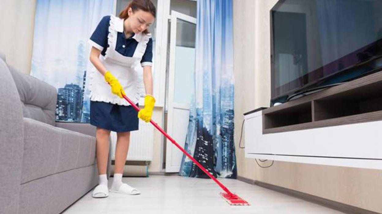 Una camarera de piso limpiando en una habitación de hotel