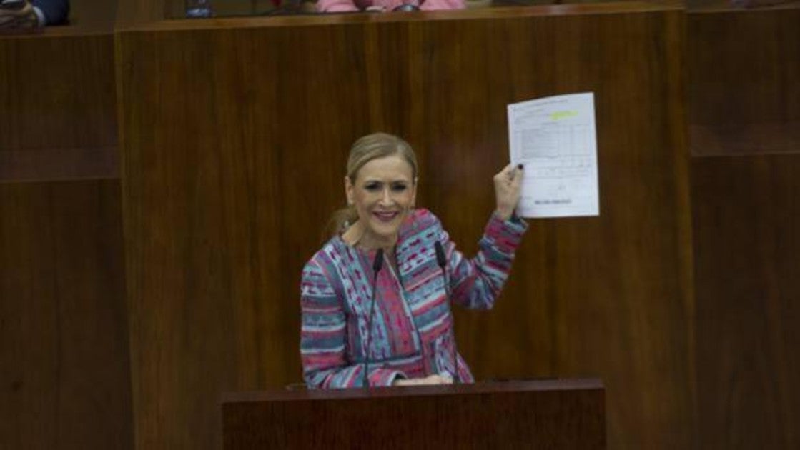 Cifuentes, en el pleno de la Asamblea de Madrid, mostrando documentación de su máster