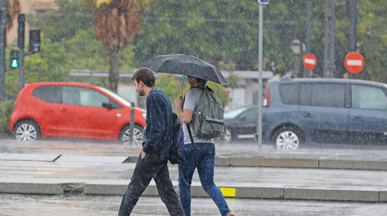 Dos jóvenes se protegen de la lluvia en los poblados marítimos de Valencia