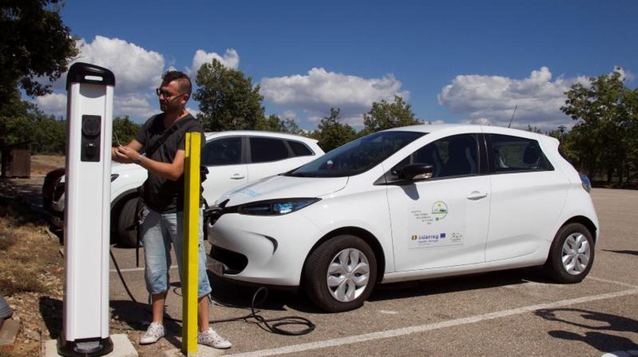 Un conductor recarga un coche eléctrico