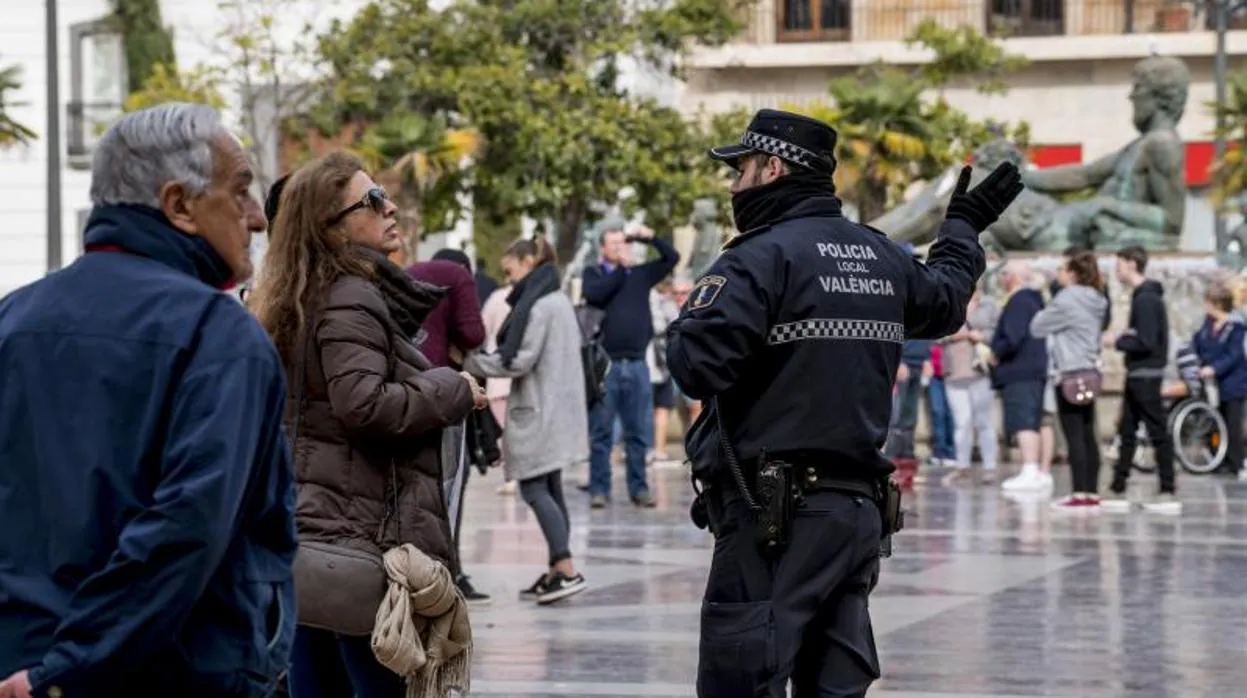Un policía local habla con una mujer en la calle en Valencia