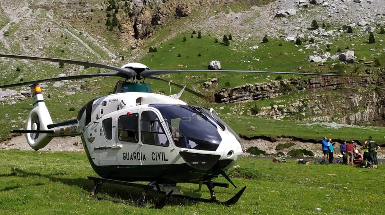 Helicóptero en el que fue evacuado el senderista. Al fondo, mientras era atendido en el lugar donde tuvo el encontronazo con las vacas de montaña, habitualmente pacíficas