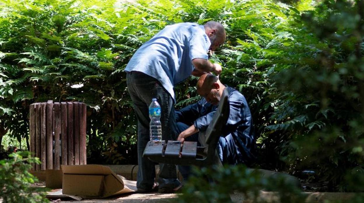 Dos ciudadanos se referescan con agua en un parque público de Lleida,