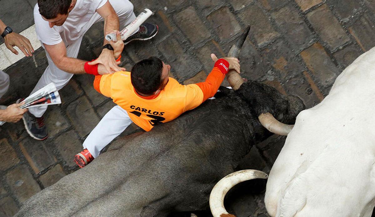 «Carlos 13» en el momento de agarrarse a un cuerno de un toro de José Escolar en el encierro del 9 de julio
