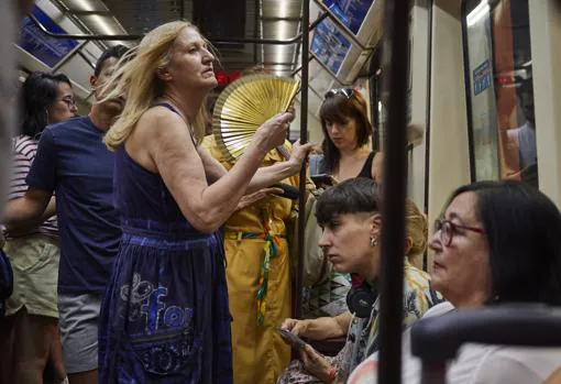 Una pasajera del metro abanicándose por el calor