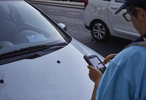 Un operario del SER apunta en su dispositivo el número de una autorización de estacionamiento