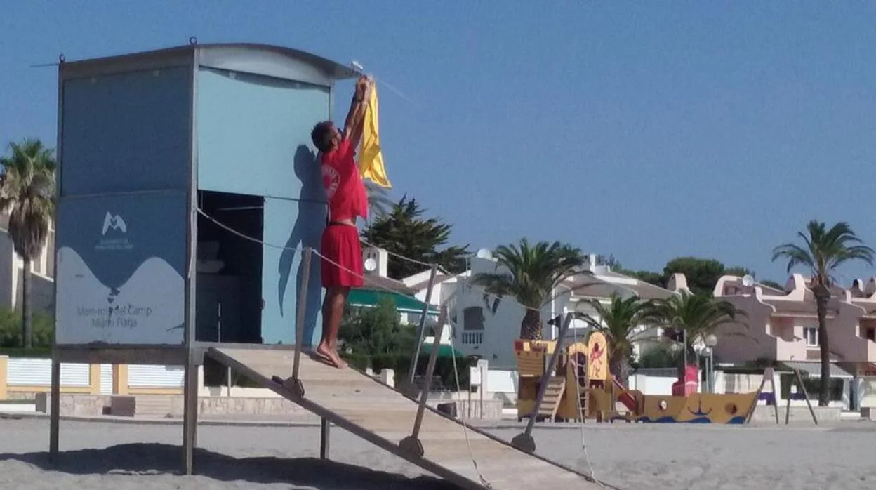 Un socorrista coloca la bandera amarilla en una playa de Cataluña