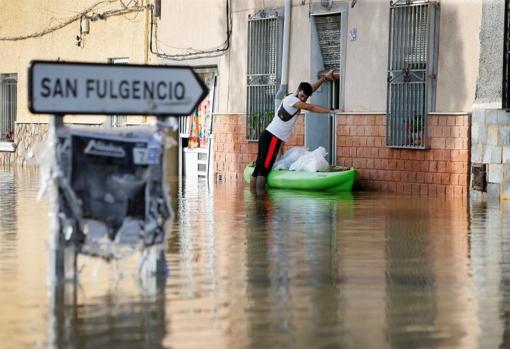 Un vecino de Dolores transporta objetos personales en una canoa al tener su casa inundada tras la DANA