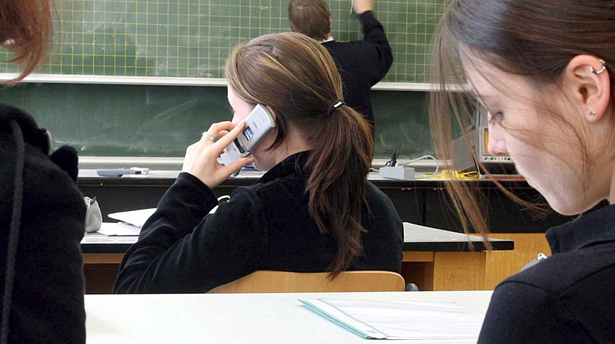 Alumna utilizando el móvil en una clase