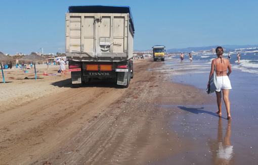 Un camión pasa entre los bañistas, este sábado a la una de la tarde en la playa del Cabanyal de Valencia