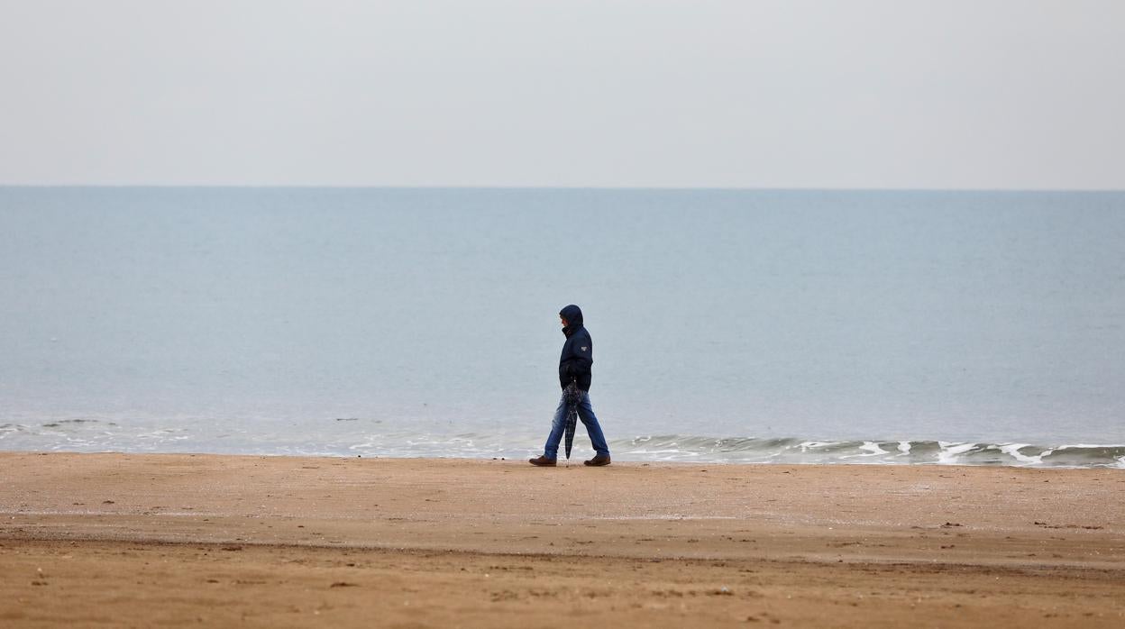 Un hombre pasea por la playa de la Malvarrosa