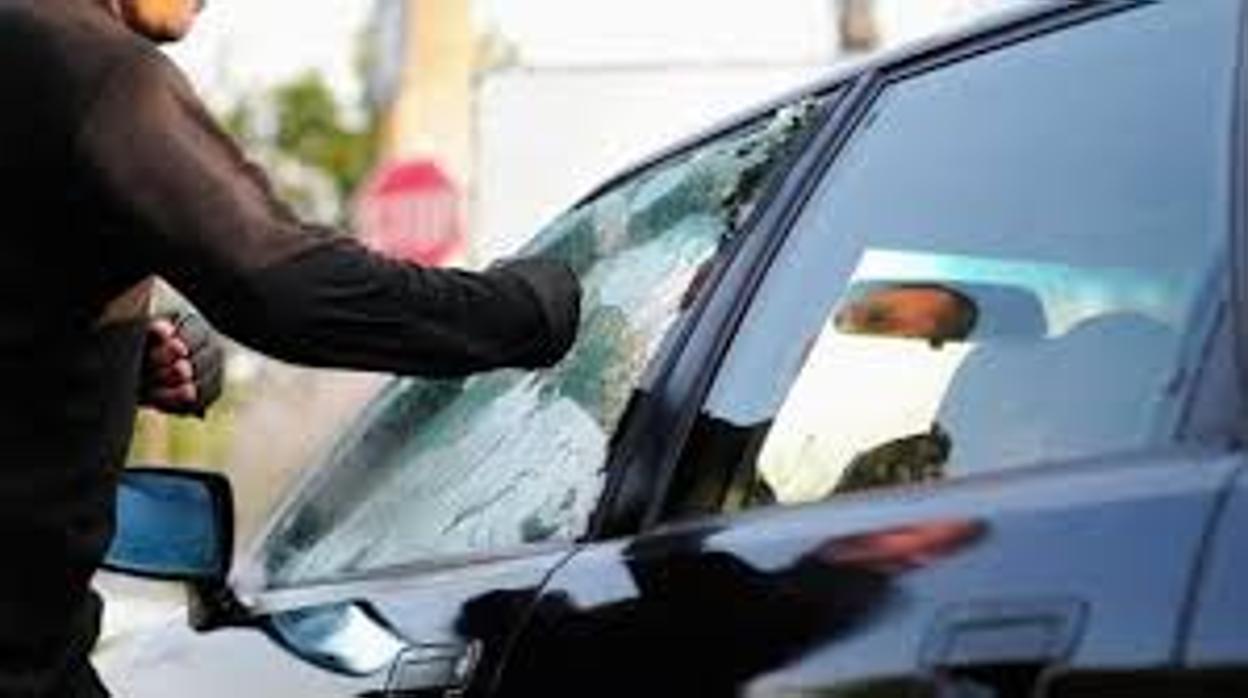 Hombre rompiendo el cristal del piloto de un coche