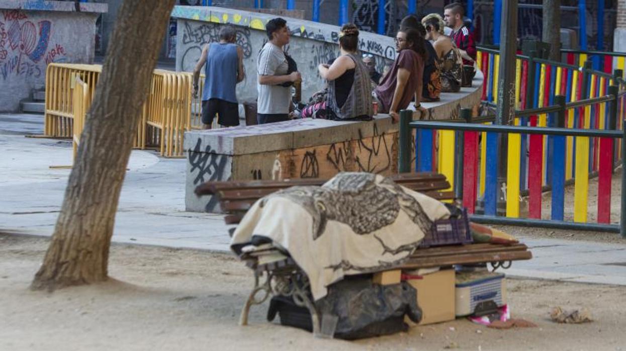 Una persona sin hogar duerme en un banco en la plaza del Dos de Mayo,