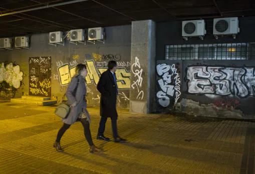Dos trabajadores caminan por uno de los pasadizos, inundado de grafitis