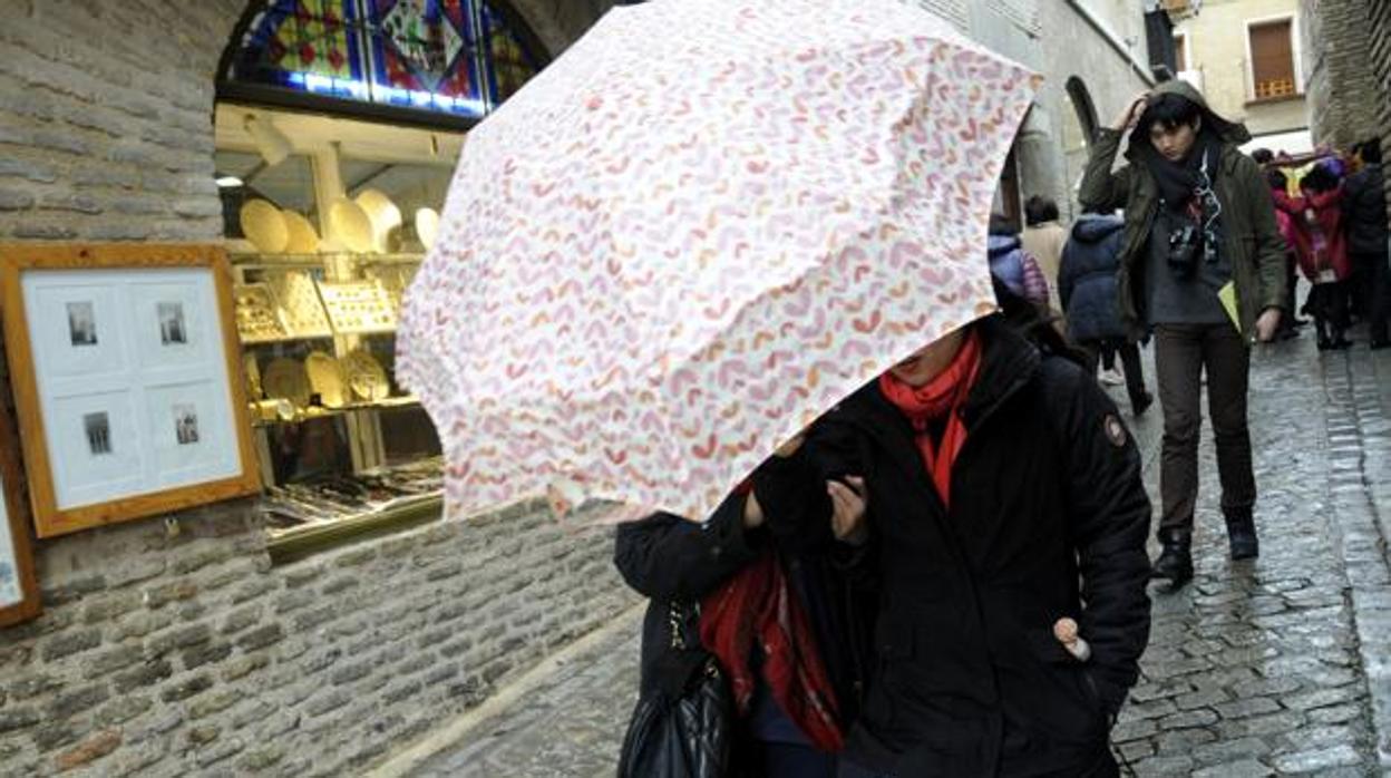 Turistas con paraguas por las calles de Toledo