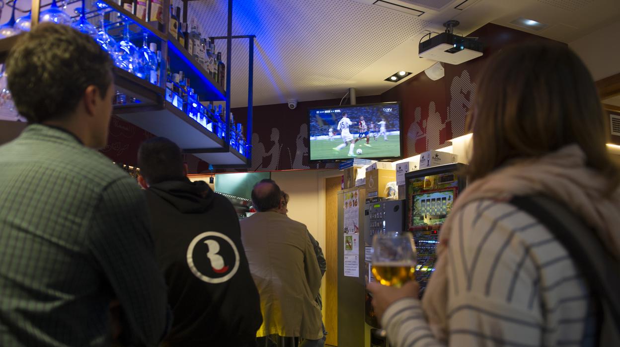 Unos clientes de un bar siguen el fútbol en la televisión