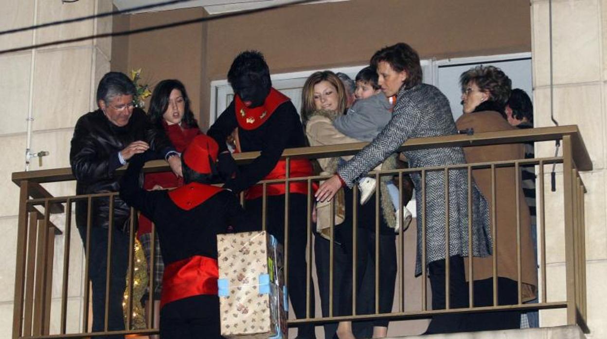 Un paje entrega un regalo en una casa de Alcoy, subido a una escalera roja, como es tradición en el cabalgata