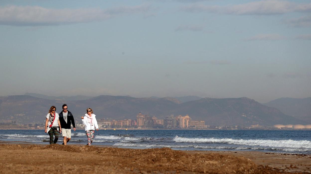 Imagen de unas personas paseando por la playa de El Cabanyal con el Golfo de Valencia al fondo