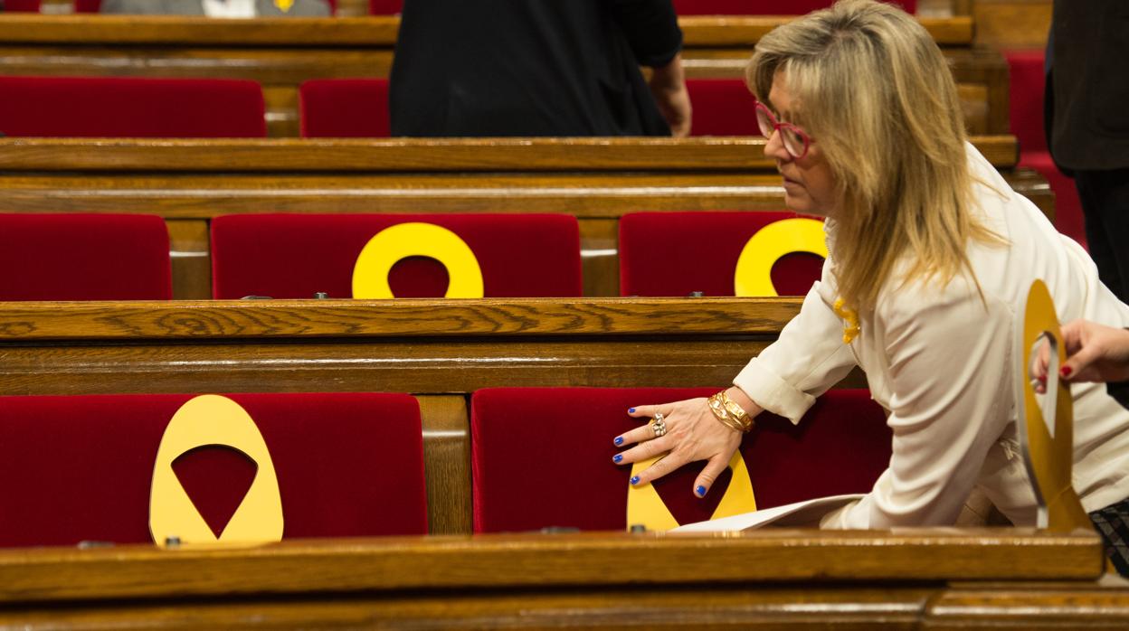 Una diputada de Junts per Catalunya coloca lazos amarillos en los escaños del Parlament