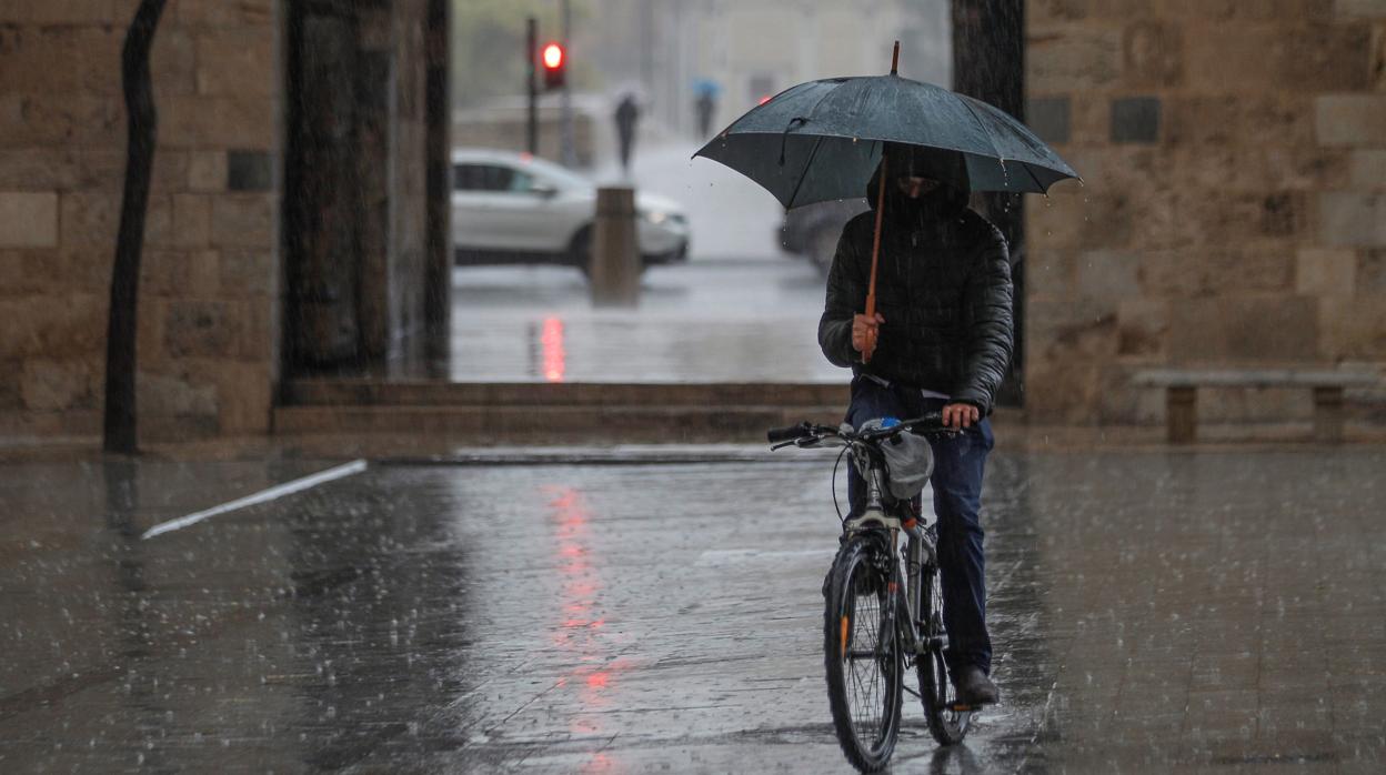 Imagen de una persona protegiéndose de la lluvia en el centro de Valencia