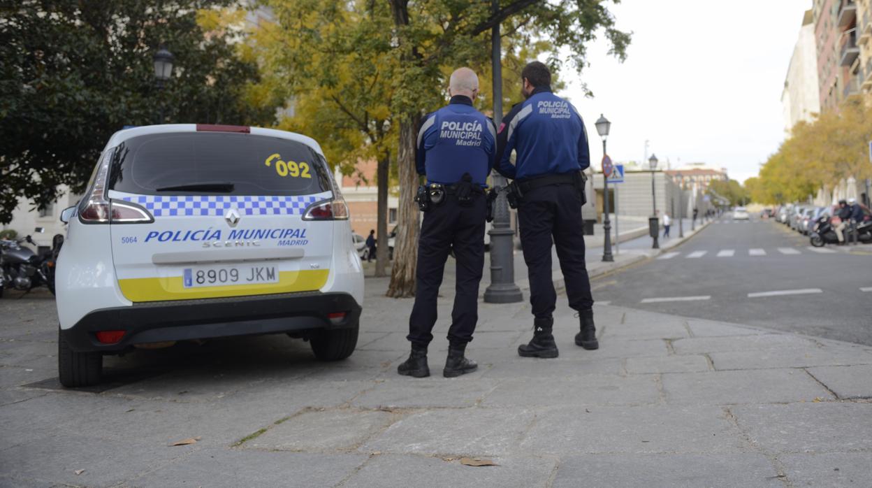 Dos agentes de la Policía Municipal, junto a un coche patrulla